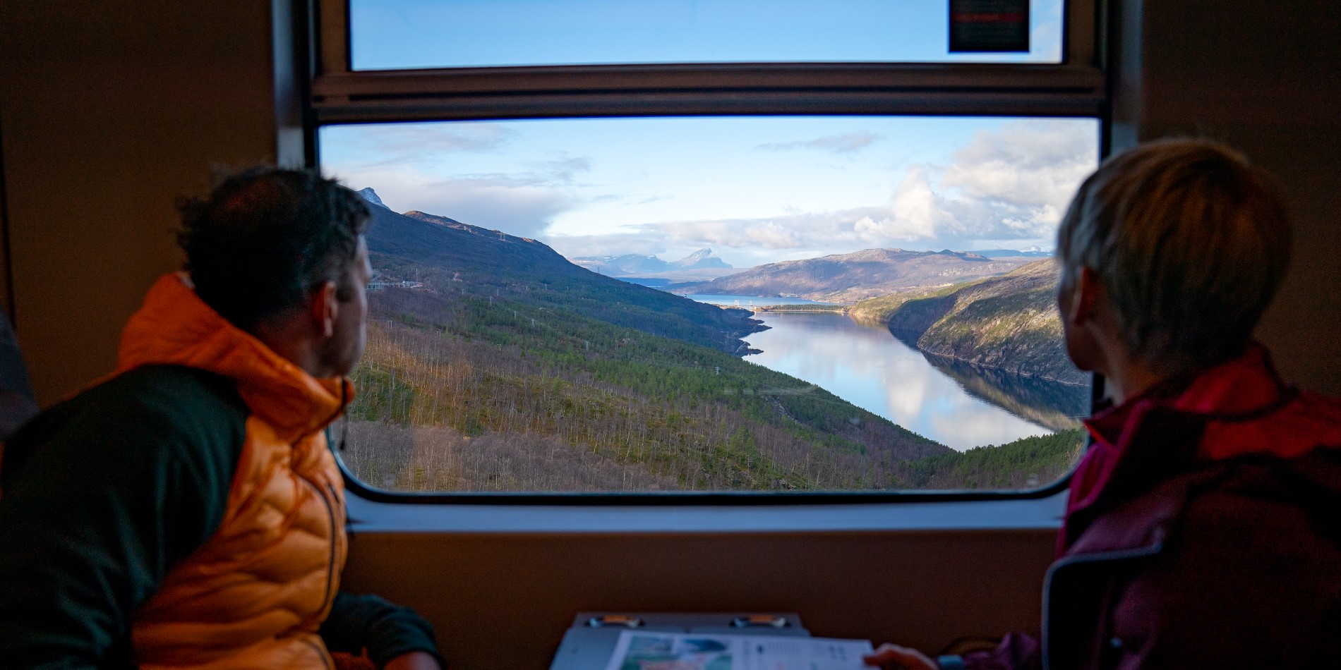 A couple looking out of the window of the Arctic Train - down on a lake