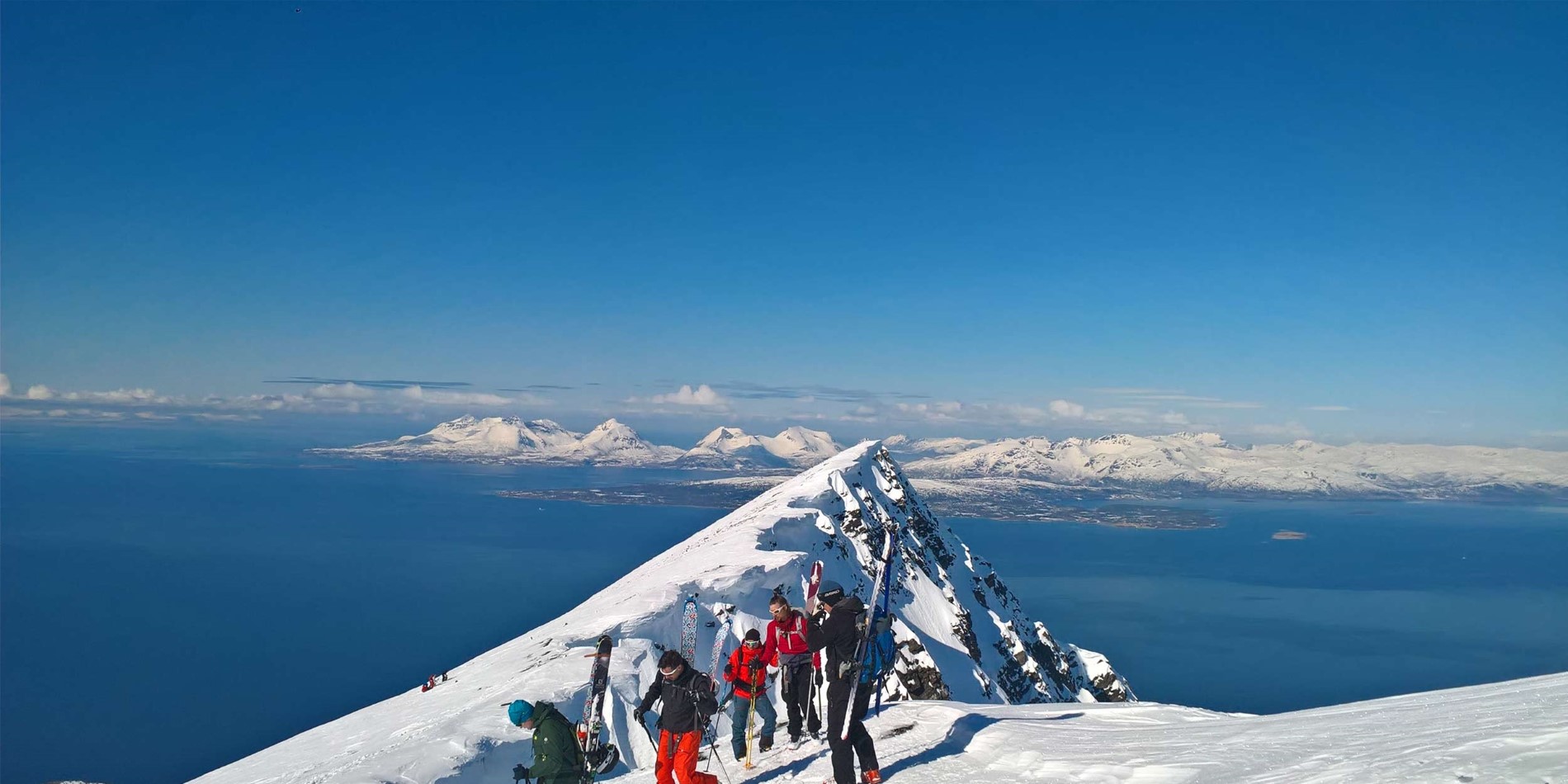 En gruppe mennesker, der står på toppen af en snedækket skråning