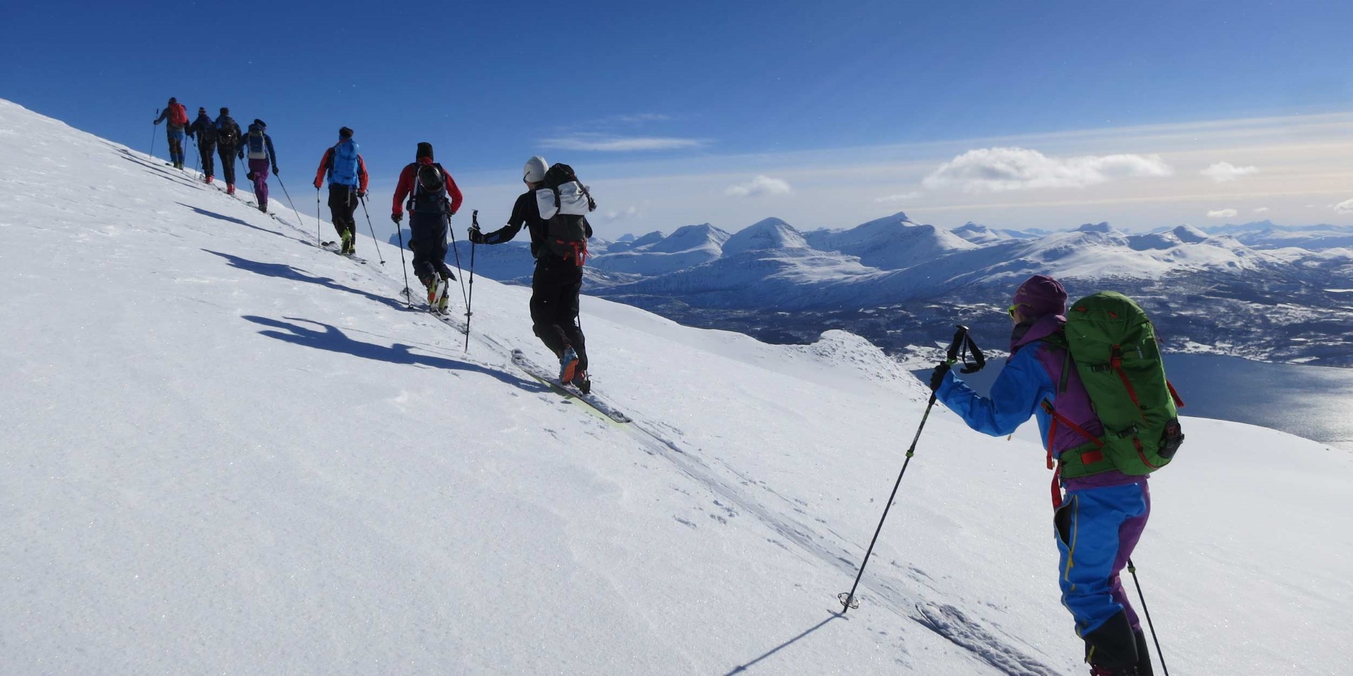 En gruppe mennesker Rider ski ned en snedækket skråning